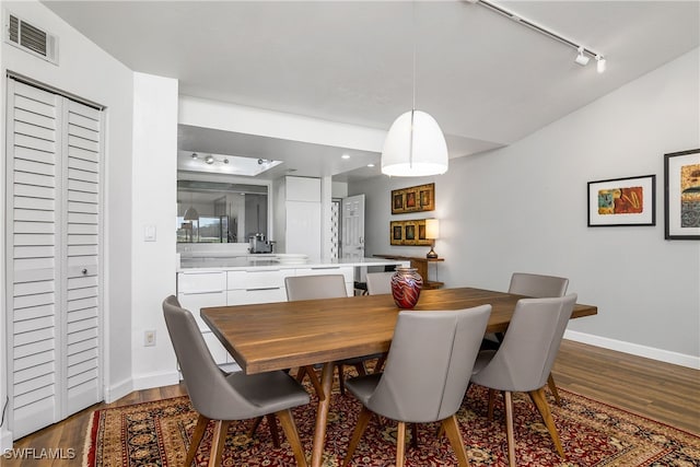 dining room with hardwood / wood-style floors, rail lighting, and vaulted ceiling