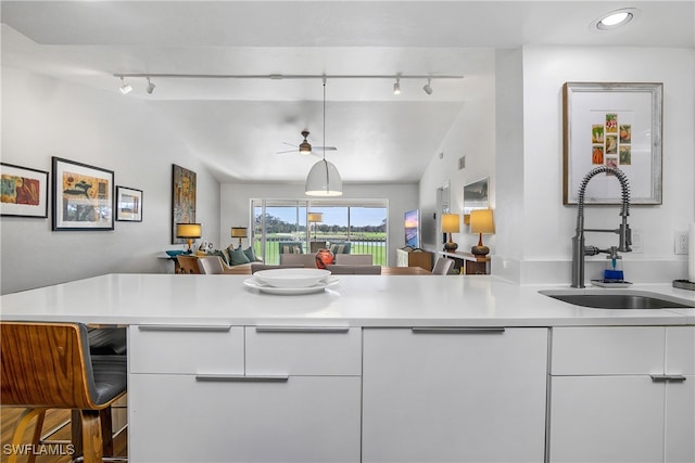 kitchen featuring ceiling fan, sink, kitchen peninsula, lofted ceiling, and white cabinets