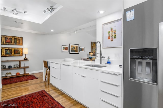 kitchen featuring sink, stainless steel fridge with ice dispenser, light hardwood / wood-style flooring, vaulted ceiling, and white cabinets