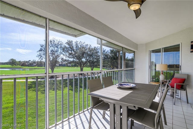 sunroom featuring ceiling fan and a water view