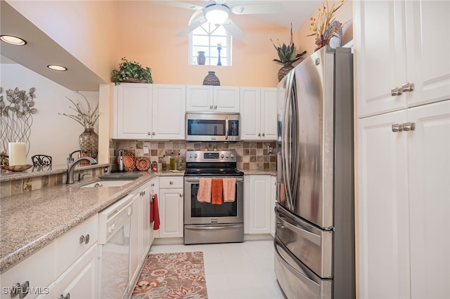 kitchen with appliances with stainless steel finishes, backsplash, sink, light tile patterned floors, and white cabinets