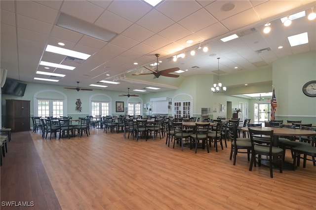 dining room with a paneled ceiling, light hardwood / wood-style flooring, and ceiling fan with notable chandelier