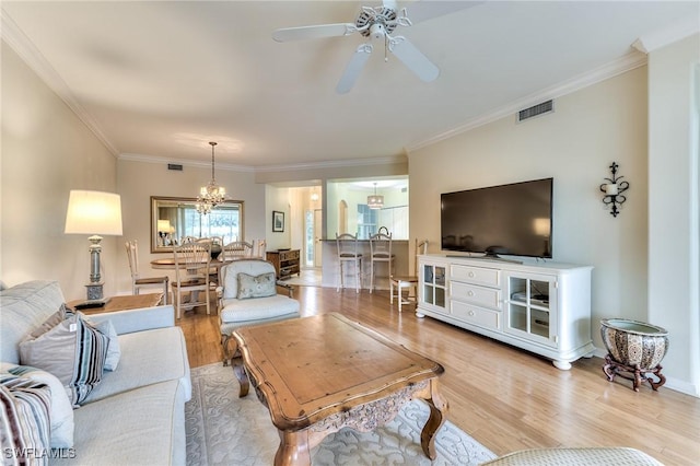 living room with crown molding, ceiling fan with notable chandelier, and light wood-type flooring