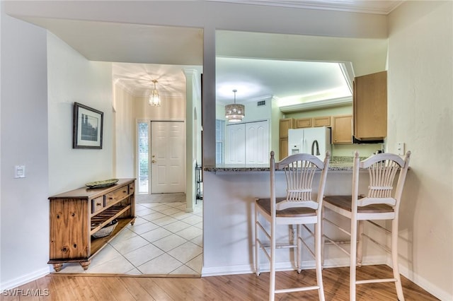 kitchen with pendant lighting, light hardwood / wood-style flooring, white fridge with ice dispenser, ornamental molding, and a notable chandelier