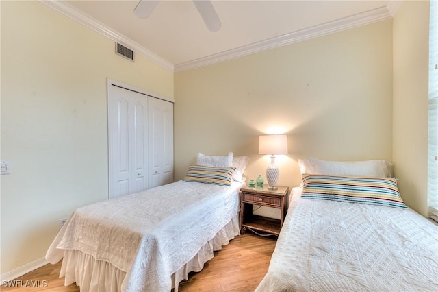 bedroom with light hardwood / wood-style floors, a closet, ornamental molding, and ceiling fan