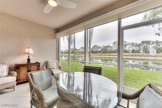 sunroom / solarium with ceiling fan and a water view