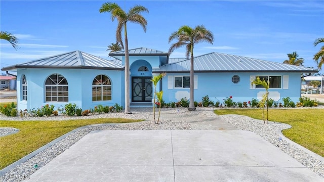 view of front of property featuring stucco siding, metal roof, and a front yard