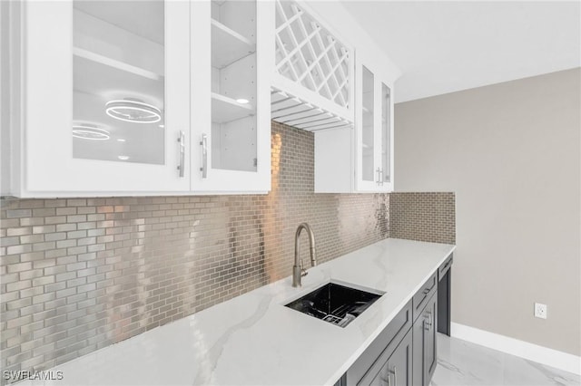 kitchen featuring gray cabinetry, sink, tasteful backsplash, light stone counters, and white cabinetry