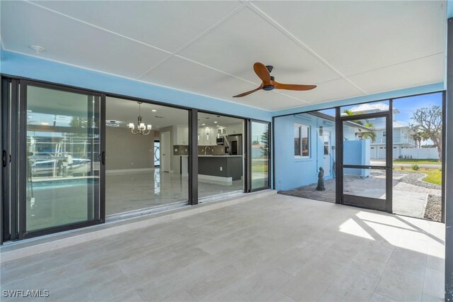 empty room featuring ceiling fan with notable chandelier and a wall of windows