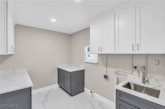 laundry room with electric dryer hookup, cabinets, and sink