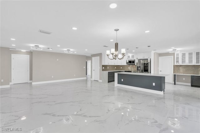 kitchen with stainless steel appliances, white cabinets, a chandelier, hanging light fixtures, and an island with sink