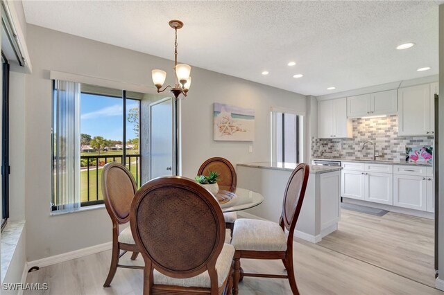 dining room with a textured ceiling, a chandelier, recessed lighting, baseboards, and light wood-style floors