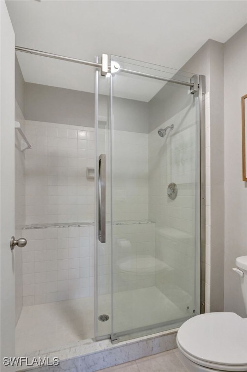 full bathroom with a stall shower, tile patterned flooring, and toilet