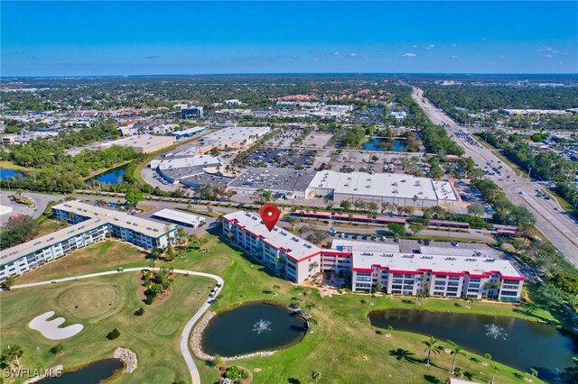 birds eye view of property with golf course view and a water view