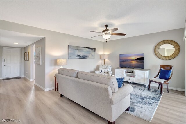 living room featuring light wood-style floors, baseboards, and a ceiling fan