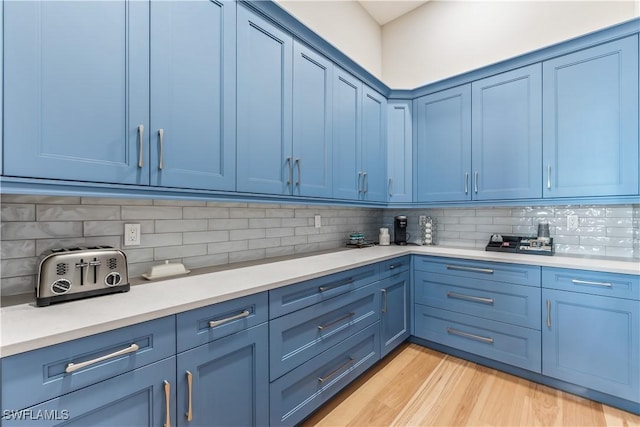 kitchen with decorative backsplash, light hardwood / wood-style floors, and blue cabinets