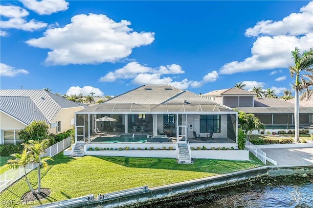 rear view of house with a water view, a patio, glass enclosure, and a lawn