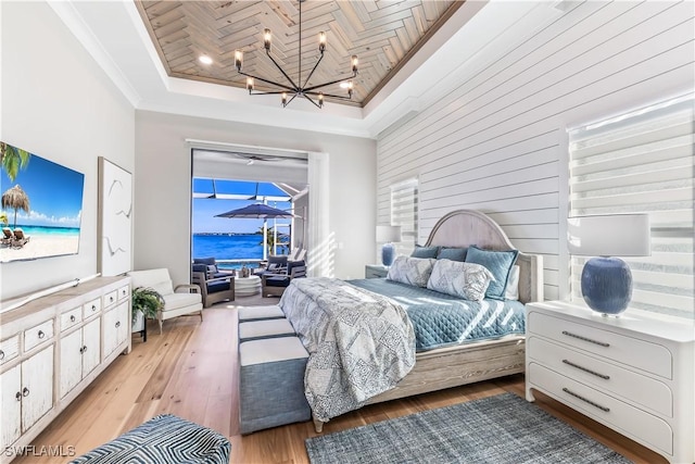 bedroom with light hardwood / wood-style flooring, a water view, wooden ceiling, a raised ceiling, and a chandelier