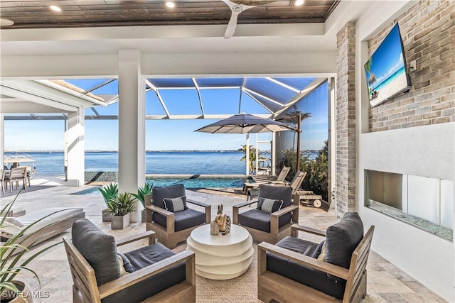 view of patio / terrace with a water view, ceiling fan, an outdoor living space, and glass enclosure