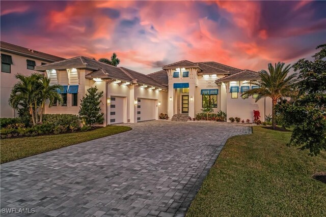 mediterranean / spanish-style house featuring a garage and a lawn