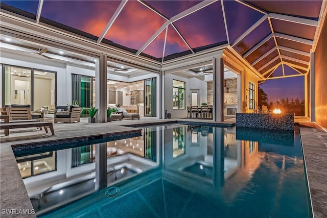 pool at dusk featuring outdoor lounge area, a patio, and a hot tub