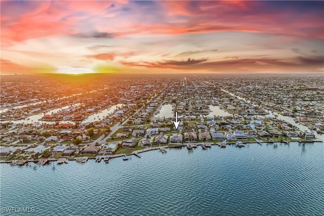 aerial view at dusk featuring a water view