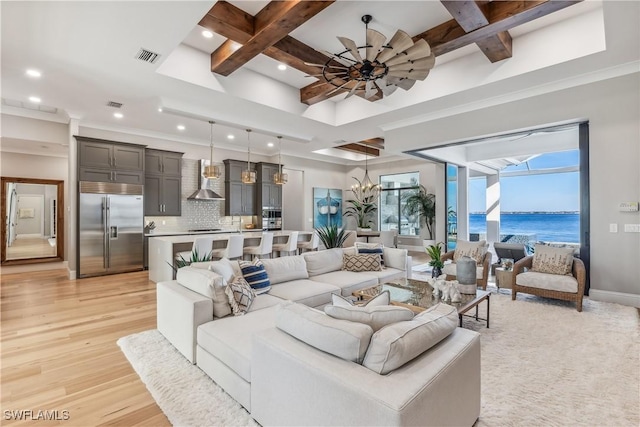 living room featuring coffered ceiling, a water view, light hardwood / wood-style flooring, beam ceiling, and ceiling fan with notable chandelier