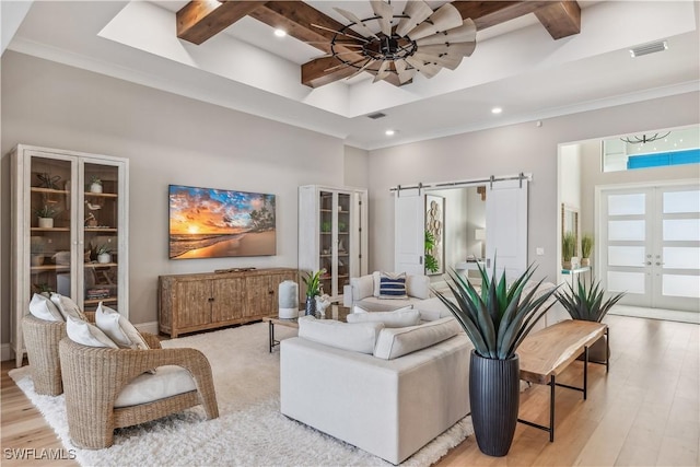 living room with french doors, a towering ceiling, a barn door, and light hardwood / wood-style floors