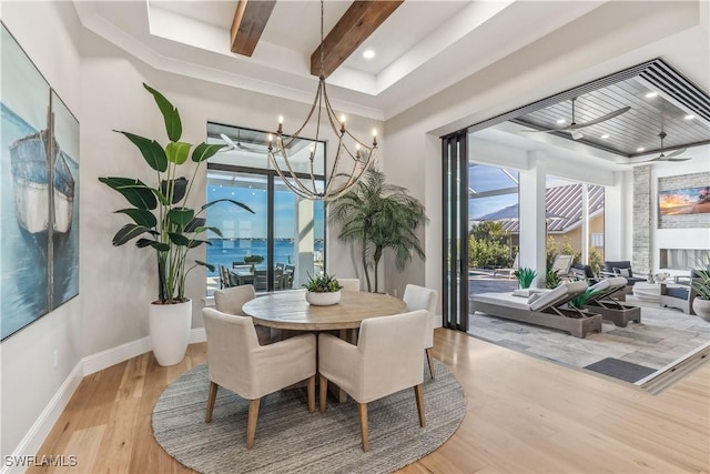 dining room featuring a water view, beam ceiling, an inviting chandelier, and light hardwood / wood-style flooring