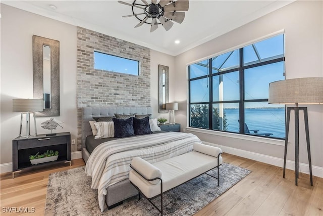 bedroom featuring multiple windows, crown molding, light hardwood / wood-style flooring, and ceiling fan