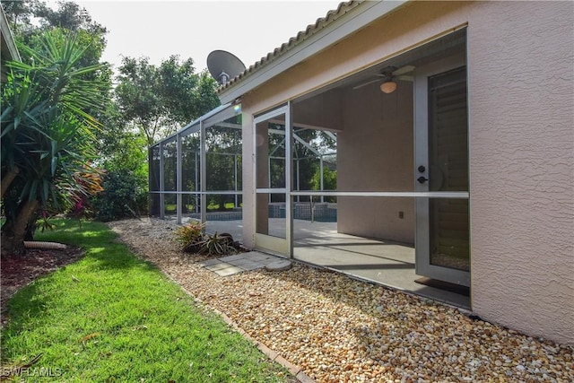 view of side of property with a yard, a patio area, ceiling fan, and a lanai