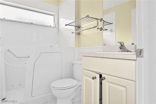 bathroom with tiled shower, vanity, and toilet