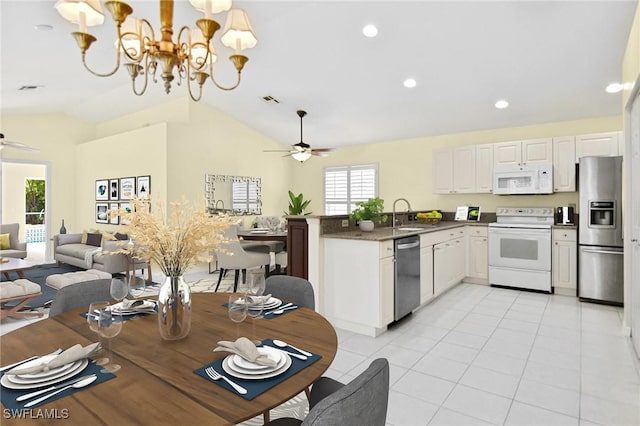 kitchen featuring lofted ceiling, ceiling fan with notable chandelier, kitchen peninsula, appliances with stainless steel finishes, and white cabinetry