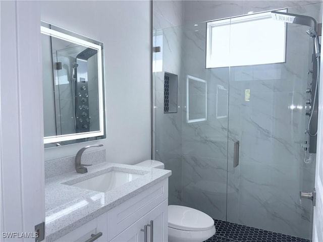 bathroom with walk in shower, vanity, and toilet