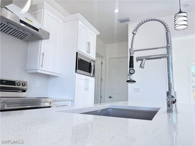 kitchen featuring white cabinets, light stone counters, stainless steel appliances, and exhaust hood