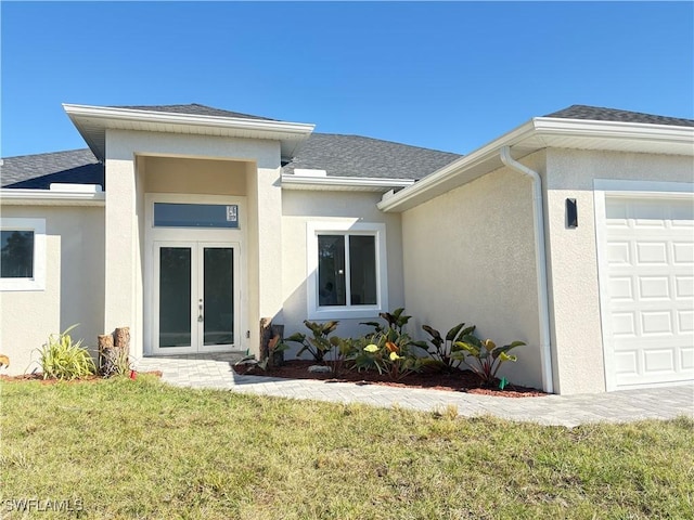 doorway to property featuring a garage, a yard, and french doors