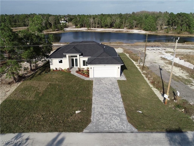 view of front of house featuring a front lawn, a water view, and a garage