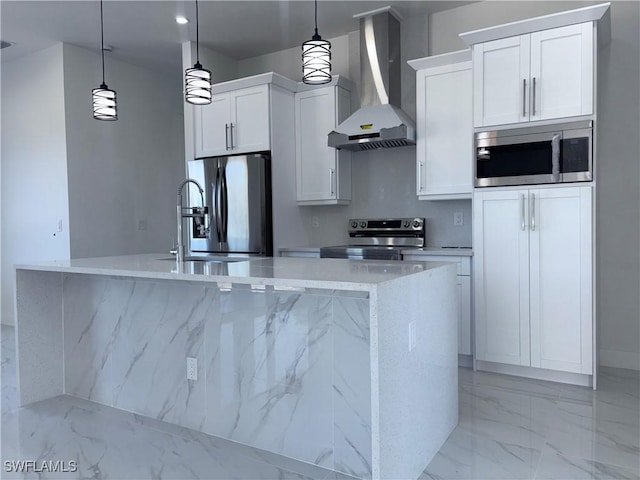 kitchen with wall chimney exhaust hood, light stone counters, decorative light fixtures, white cabinets, and appliances with stainless steel finishes