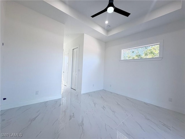 empty room featuring ceiling fan and a tray ceiling