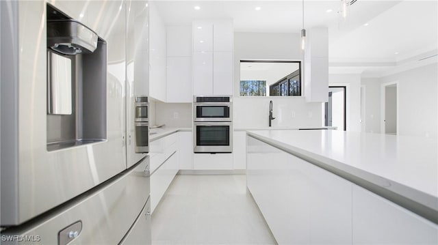 kitchen featuring sink, white cabinetry, stainless steel appliances, and hanging light fixtures