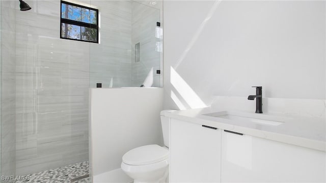 bathroom featuring vanity, toilet, and a tile shower