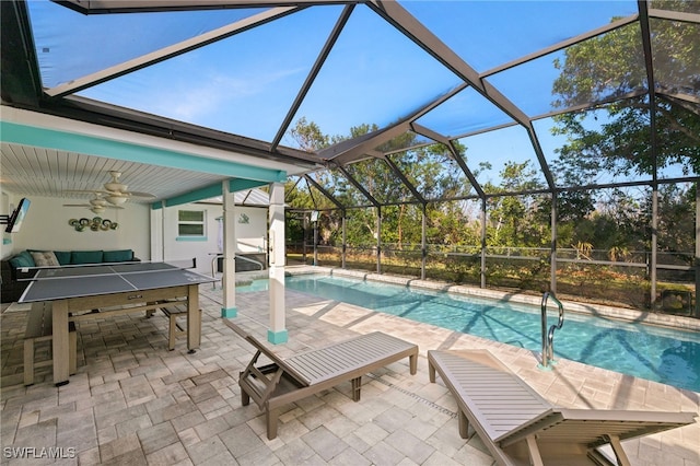 view of swimming pool with ceiling fan, a patio, and glass enclosure