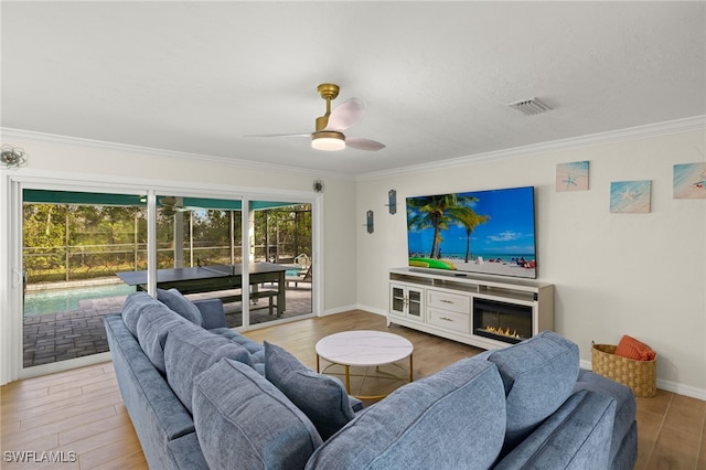 living room with ceiling fan, wood-type flooring, crown molding, and a wealth of natural light