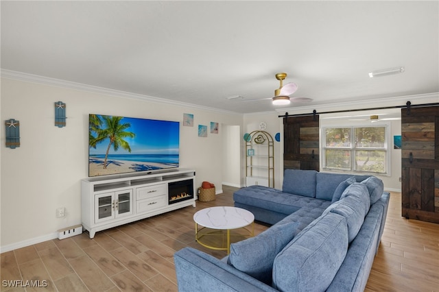 living room featuring wood-type flooring, a barn door, ceiling fan, and crown molding