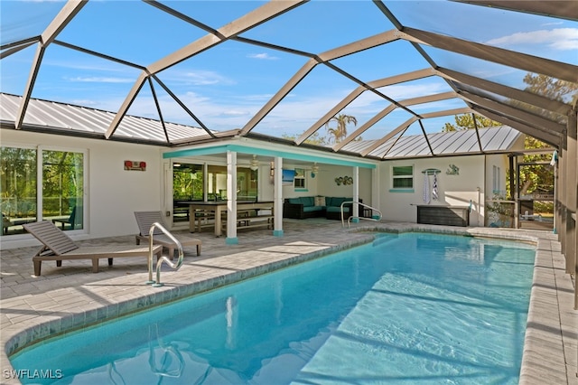 view of pool with an outdoor living space, ceiling fan, a patio, and glass enclosure