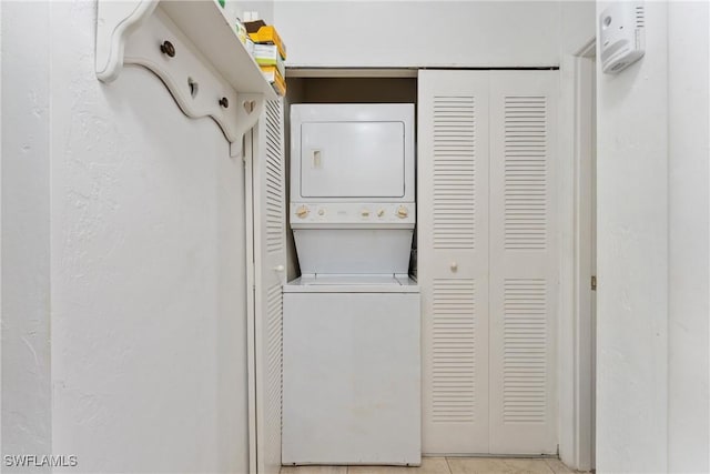 laundry room with light tile patterned floors and stacked washing maching and dryer