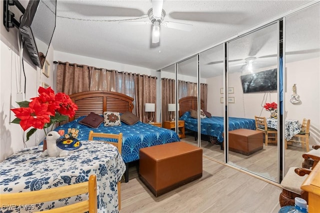 bedroom with a textured ceiling, a closet, light hardwood / wood-style flooring, and ceiling fan