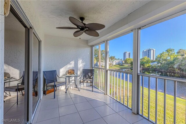 sunroom / solarium with a water view and ceiling fan