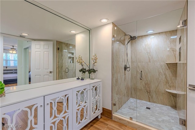 bathroom featuring hardwood / wood-style floors, ceiling fan, walk in shower, and vanity