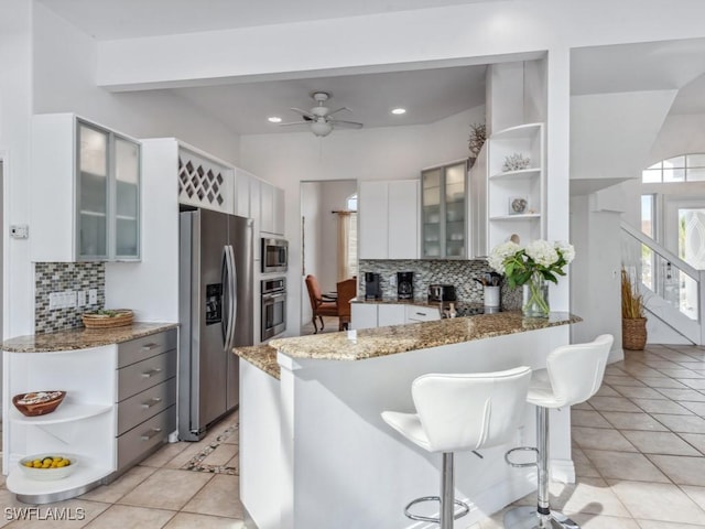 kitchen featuring white cabinets, backsplash, stainless steel appliances, and light tile patterned flooring